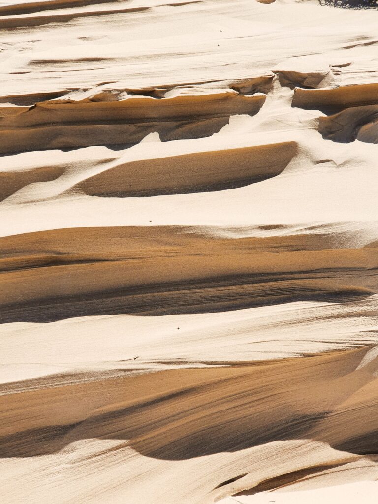 Close-up of layered sand patterns in natural rock formations creating a smooth, textured surface.